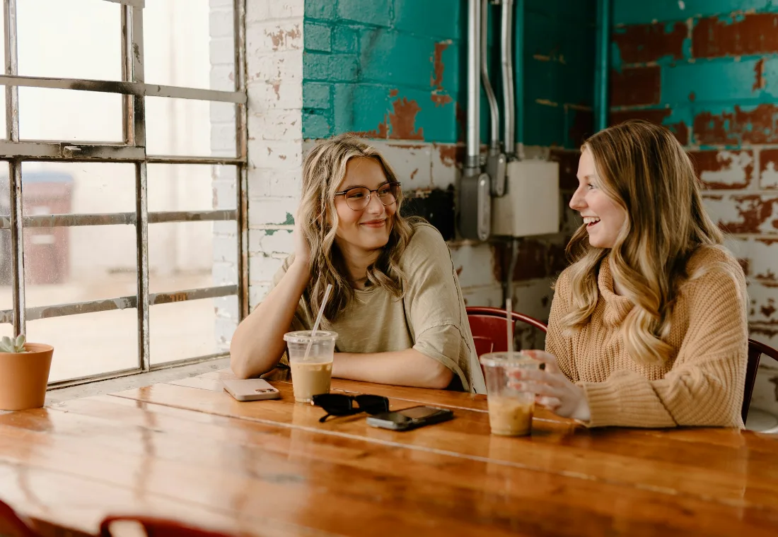 Two friends catching up over coffee at a bright cafe table