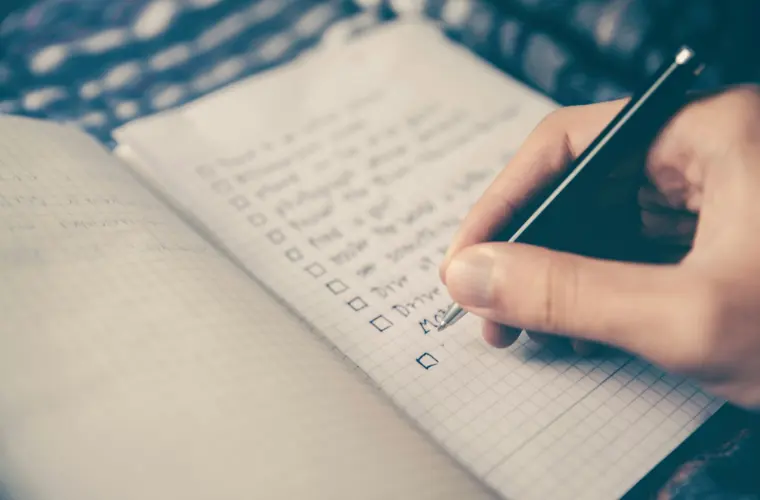 A hand ticking items off a handwritten checklist.
