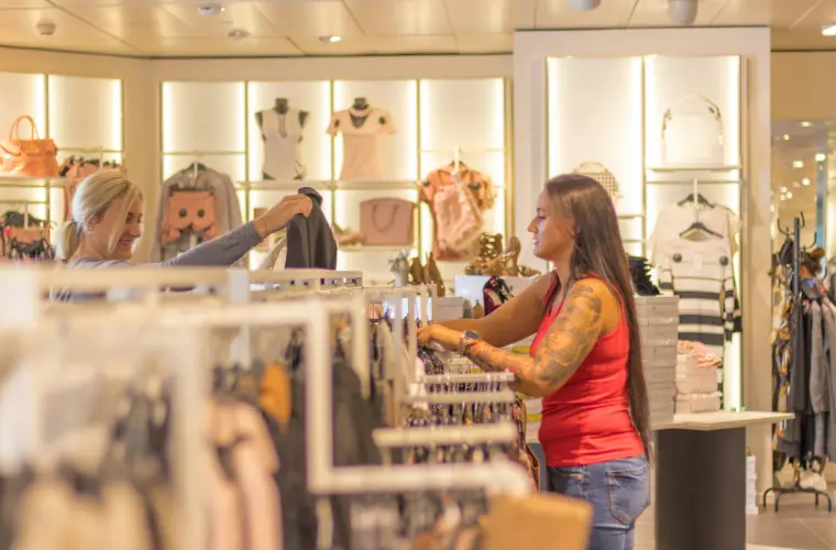 Shoppers browsing rails of clothing inside a boutique.