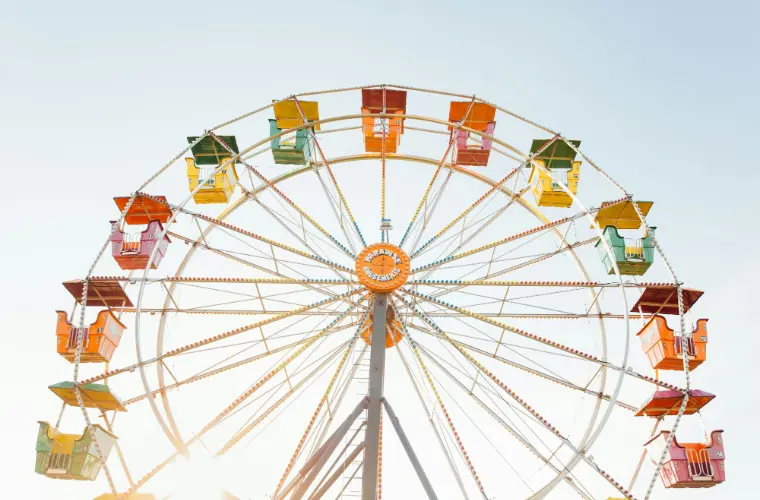 A brightly painted fairground wheel against a clear sky.