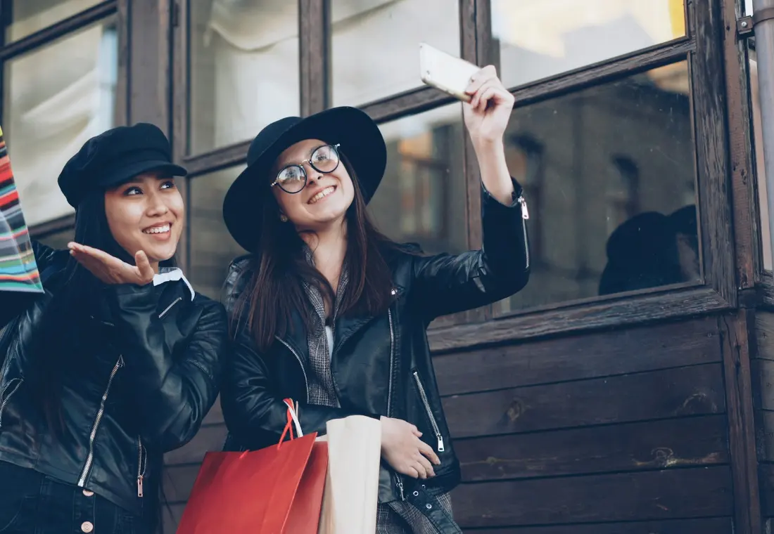 Two friends laughing together with shopping bags after a day out.