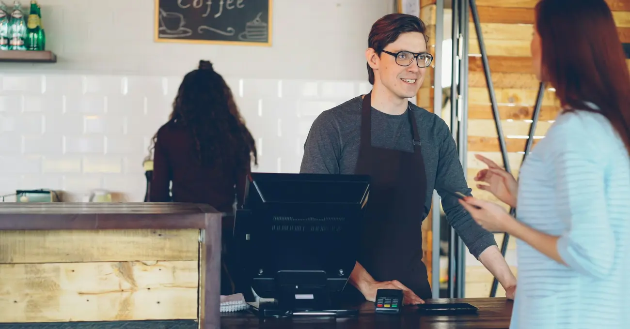 A customer paying at a café counter while the barista serves them.
