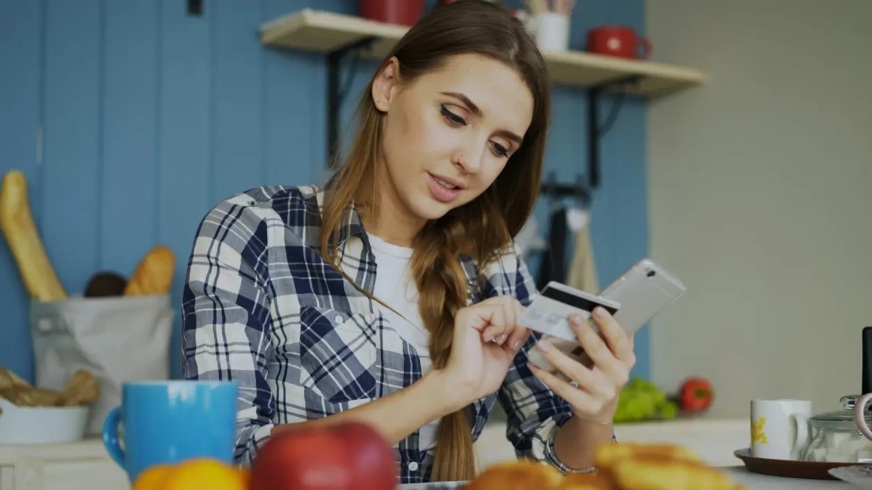 A person checking their phone over breakfast at the kitchen table.