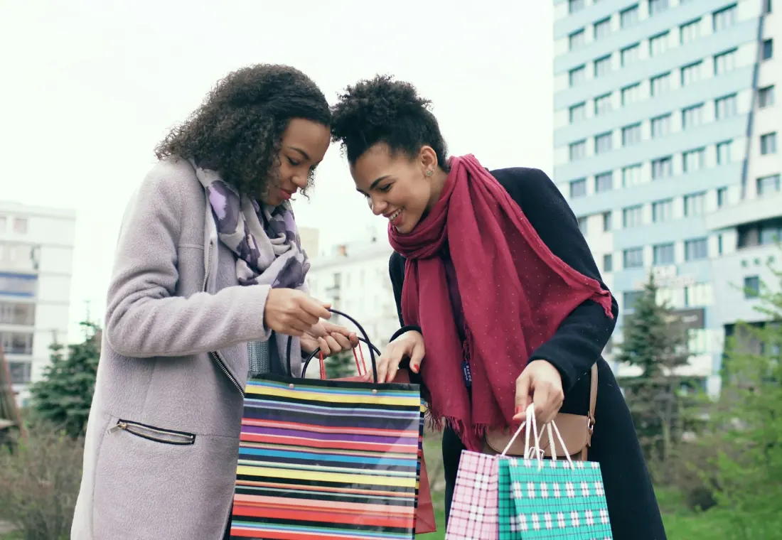 A woman sharing what she bought with a friend after a day of shopping.