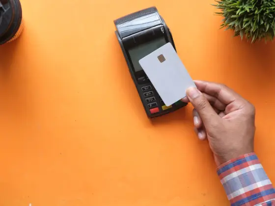 A bank card being tapped on a payment terminal at a counter.